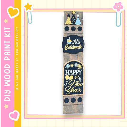 a wooden sign with various festive and celebratory messages, including "Let's Celebrate", "Happy New Year", and "If we can create it, we can make it!" The sign is displayed against a pink and yellow background with decorative elements such as hearts and stars.