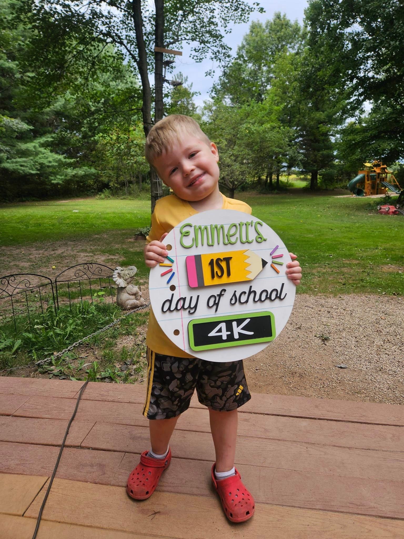 a young boy holding a sign that says emmett's 1st day of school