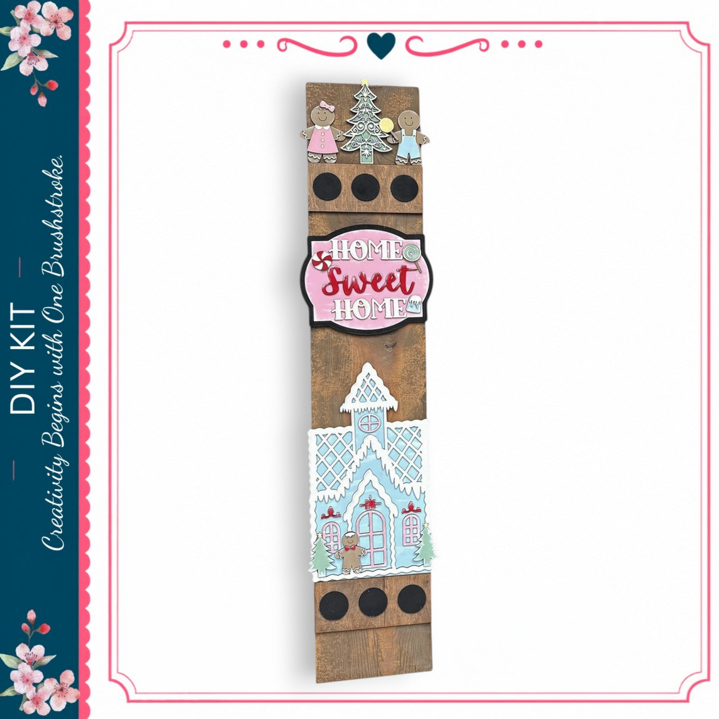 a wooden sign with a winter theme, including a gingerbread house and snowflakes. The sign has a pink and white color scheme and displays the text "Home Sweet Home" in a decorative font.
