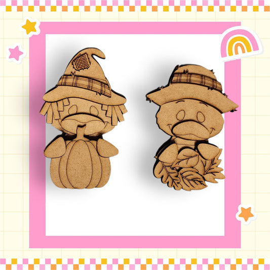 two wooden cutouts of cartoon characters, one wearing a witch's hat and the other wearing a hat with leaves, set against a pink and yellow checkered background.