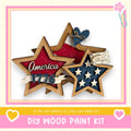 The image is a DIY wood paint kit featuring a wooden star-shaped decoration with the word "America" written on it, along with a heart-shaped decoration. The kit appears to be made of wood and is designed for creating similar star-shaped decorations.