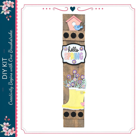 a vertical wooden sign with various decorative elements, including a birdhouse, flowers, and a yellow rain boot. The sign has a "Hello Spring" sign on it, indicating the arrival of spring.