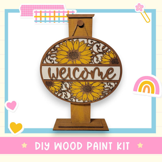 a wooden welcome sign with a sunflower design, surrounded by various colorful stickers and illustrations.