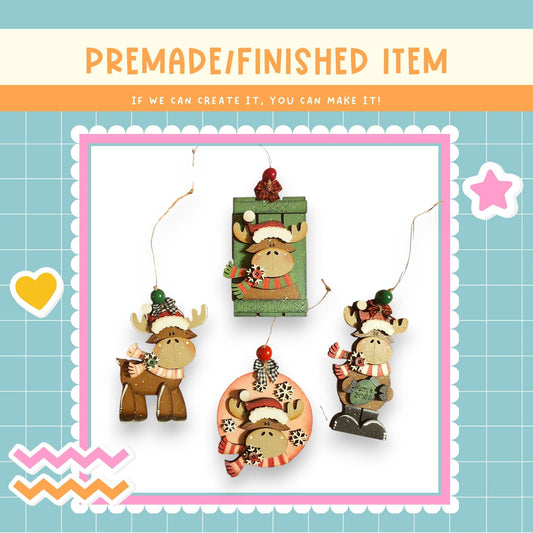 a collection of four ornaments, each depicting a moose wearing a hat and scarf. The ornaments are hanging from strings, creating a festive and decorative display.