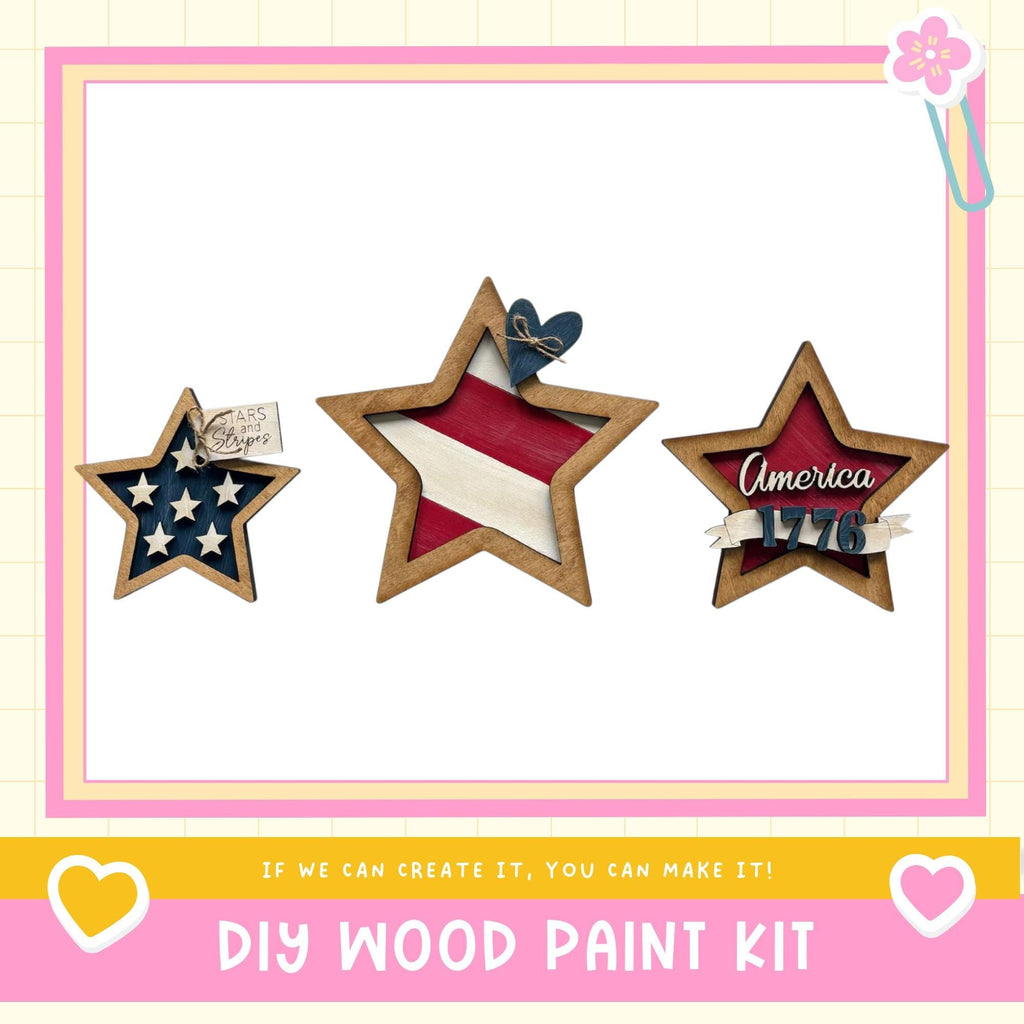 three wooden stars, each with a different design and color, arranged in a row. The stars are decorated with American flags and the word "America" written on them. The image also includes text that says "DIY WOOD PAINT KIT" and a heart symbol, suggesting that this is a kit for creating wooden stars.
