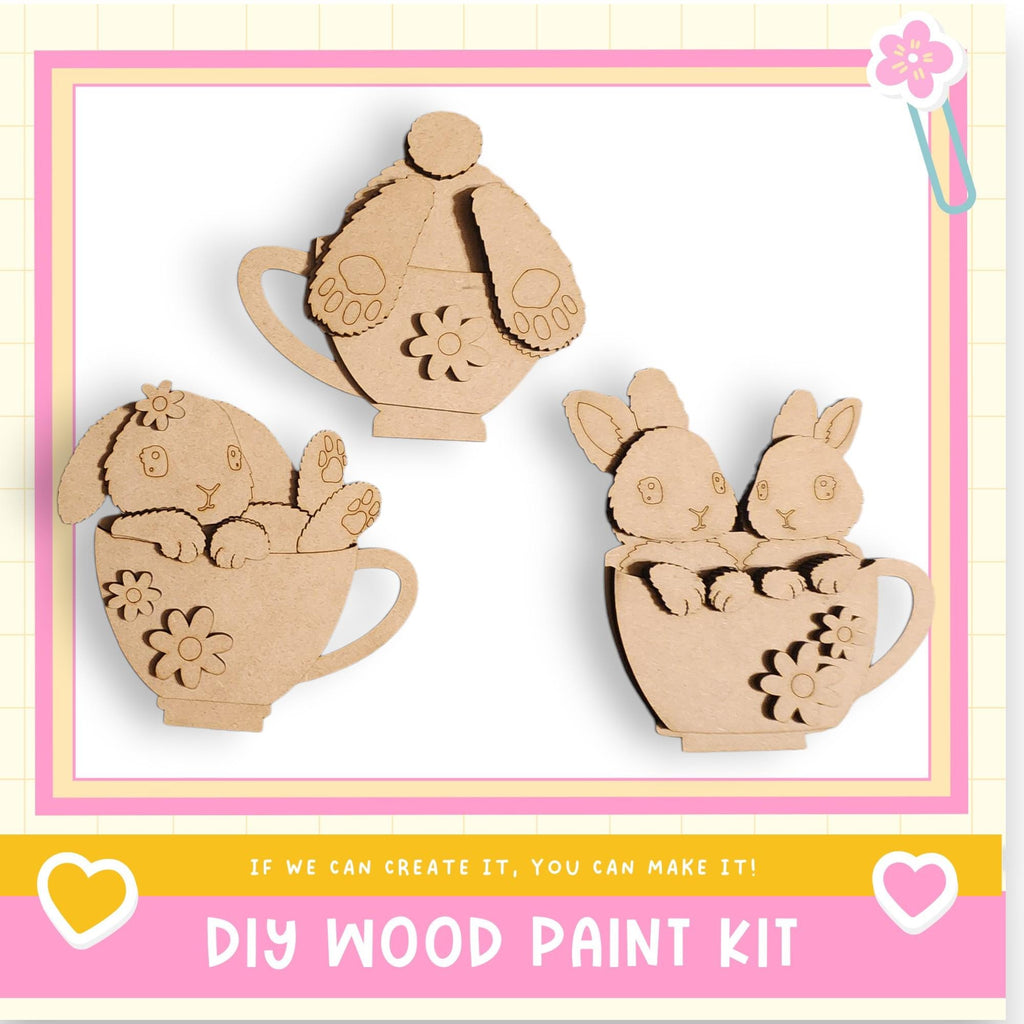 three wooden cutouts of rabbits in cups, arranged in a row.