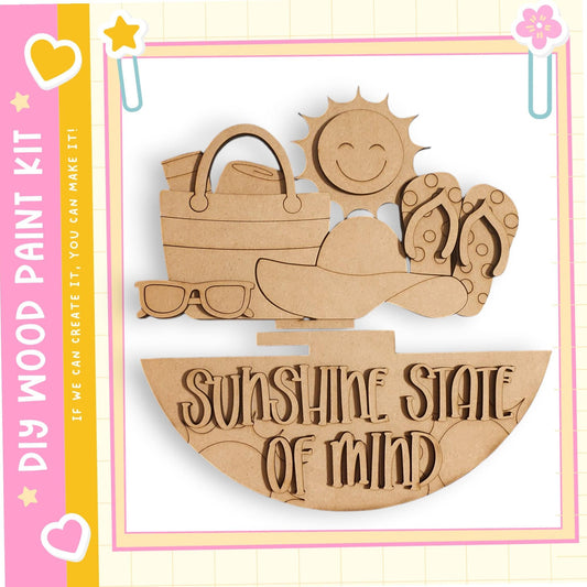 The image is a wooden paint kit featuring a sun and various beach-related items, such as a hat, sunglasses, and a beach bag.