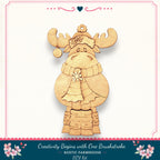 A wooden ornament in the shape of a moose, wearing a scarf and hat, is displayed against a white background.