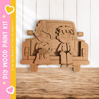 A wooden paint kit depicting a bride and groom sitting in the back of a truck.