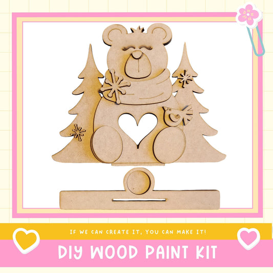 a DIY wood paint kit, with a wooden bear figure and pine trees as the main decorative elements.