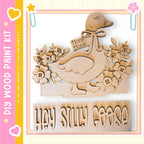 a wooden cutout of a goose with a bow, surrounded by flowers, and the text "Hey Silly Goose" below it.