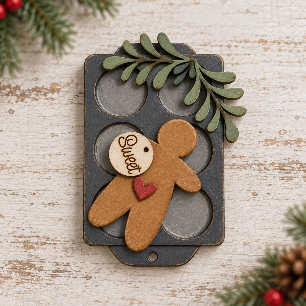 A wooden gingerbread man figure with a heart-shaped tag attached to it, placed on a wooden surface with pine branches and red berries in the background.