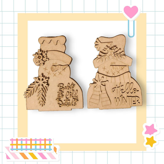 two wooden snowman ornaments with text on them, set against a background with a grid pattern.