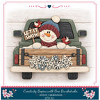A wooden truck decorated with a snowman, birds, and snowflakes, with a sign that says "LET IT SNOW".