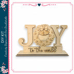 a wooden sign with the word "Joy" carved into it, along with a wreath design.