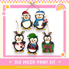 A DIY wood paint kit for creating ornaments in the shape of penguins, featuring five different penguin designs in various colors and styles.
