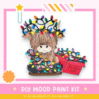 A wooden paint kit with a cartoon cow wearing a crown of colorful Christmas lights.