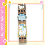 The image is a wooden frame with a decorative border, featuring illustrations of a white goose and flowers. The frame is set against a pink and yellow background with decorative elements such as hearts and stars.