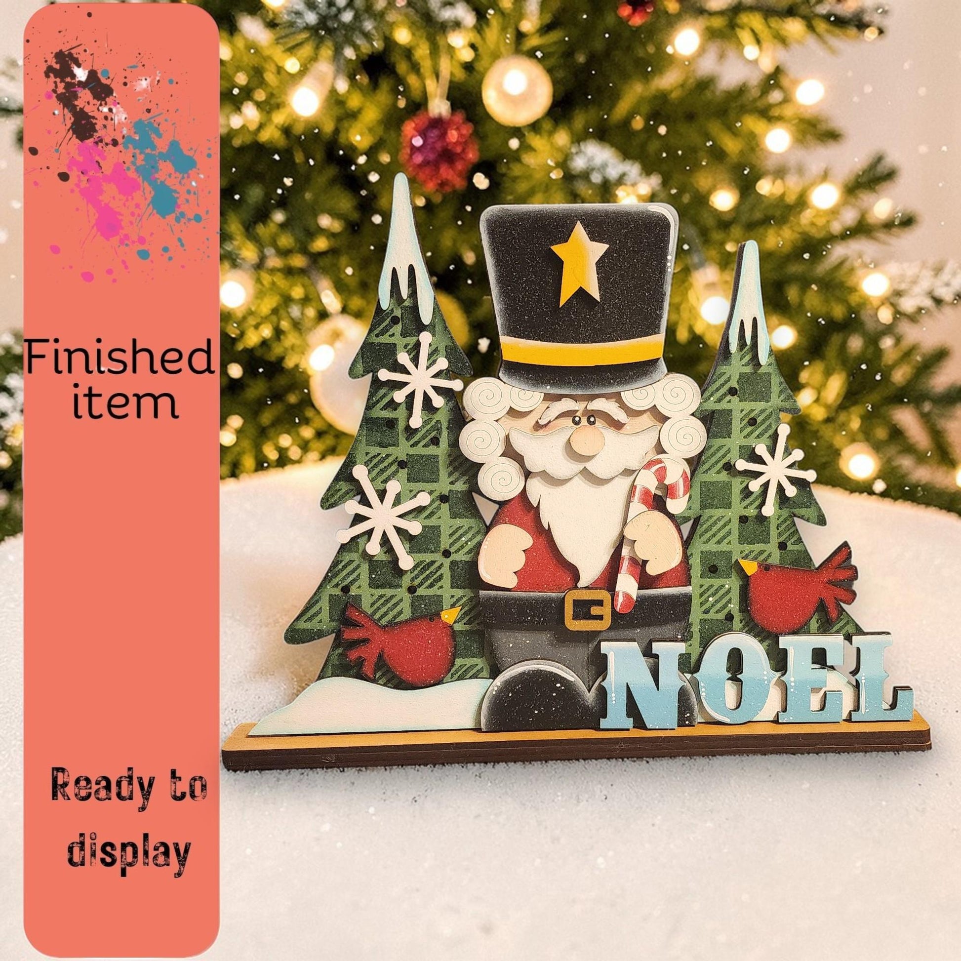 A Christmas tree with a nutcracker figure and snowflakes, along with the word "Noel" displayed on a wooden base.