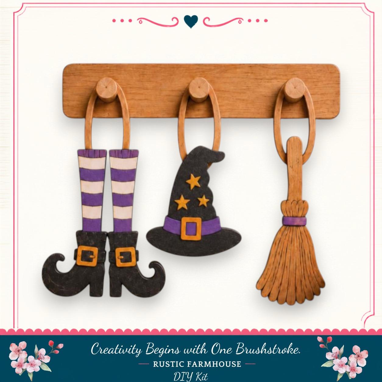 a rustic farmhouse-style DIY kit for creating Halloween decorations, including a wooden hanger with three wooden charms hanging from it. The charms are designed to resemble a witch's broom, a witch's hat, and a pair of purple and white striped boots.