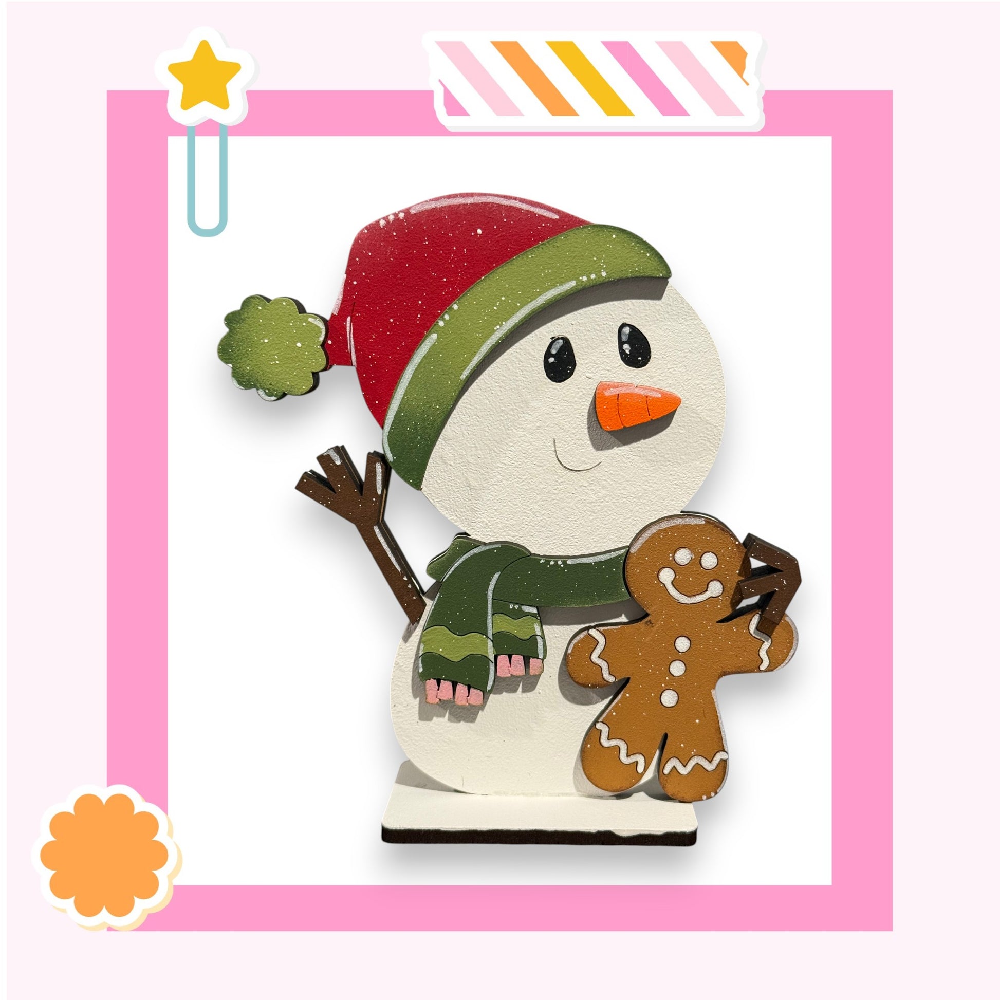 A cheerful snowman figure holding a gingerbread man figure, set against a pink background with a star decoration.