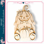 A wooden Halloween pumpkin decoration with a carved face and leaves, sitting on a white background.