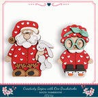 two wooden cutouts of Santa Claus and a young girl, both wearing red and white polka dot outfits with a red bow on their heads.