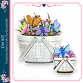 a white basket filled with colorful flowers and butterflies, with a smaller basket containing more flowers and butterflies.