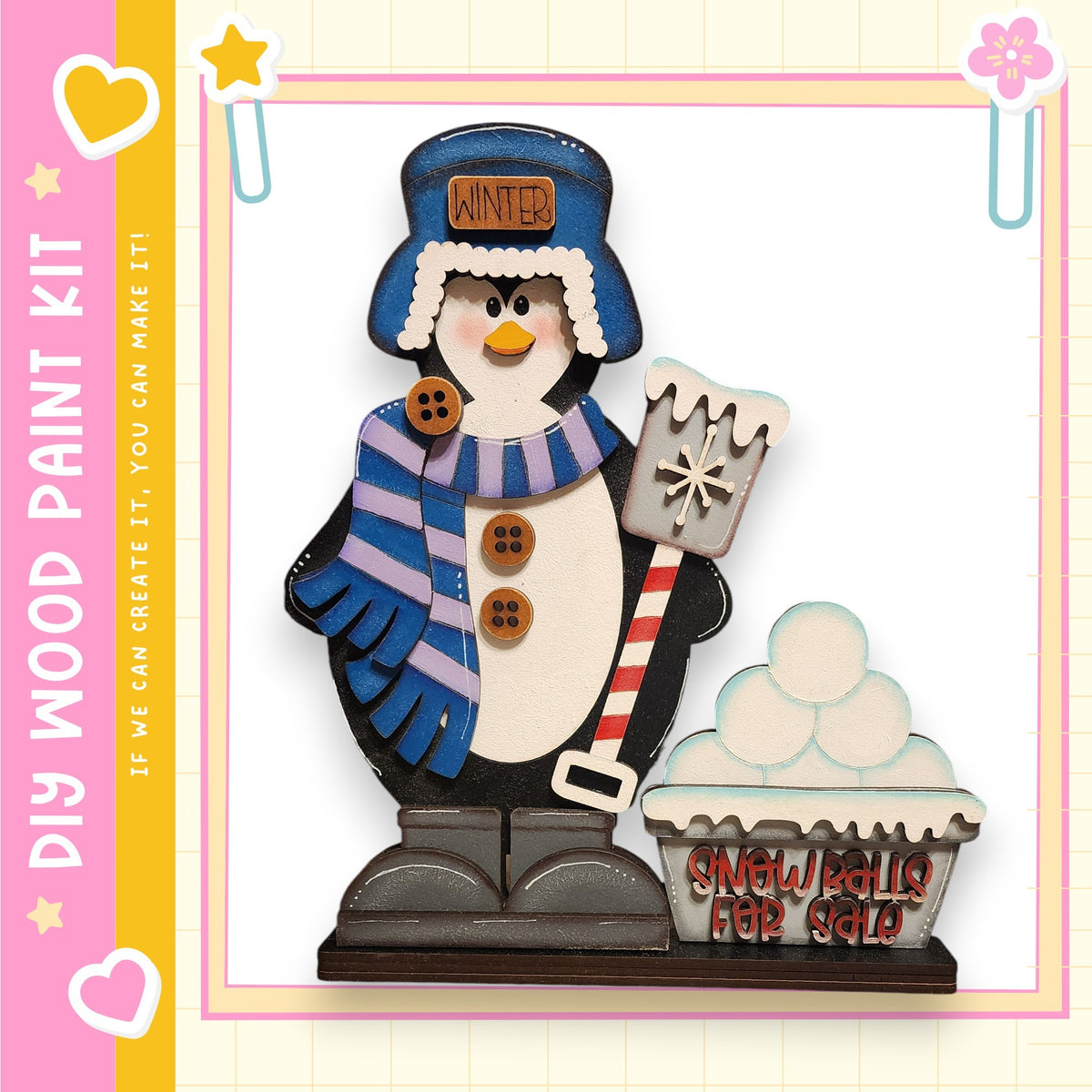 A wooden snowman figure holding a snow shovel and standing next to a snow ball bin, with a pink and yellow border.
