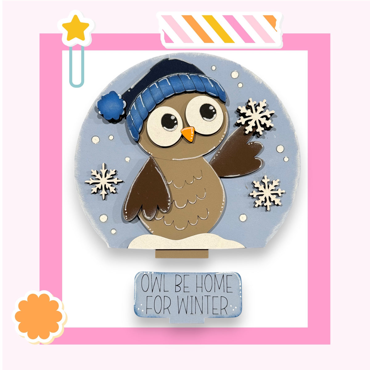 A snow owl wearing a blue hat and holding a snowflake is surrounded by snowflakes and the text " Owl be home for winter."
