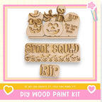 The image is a promotional poster for a DIY wood paint kit, featuring a skeleton, jack-o-lantern, and tombstone decoration.
