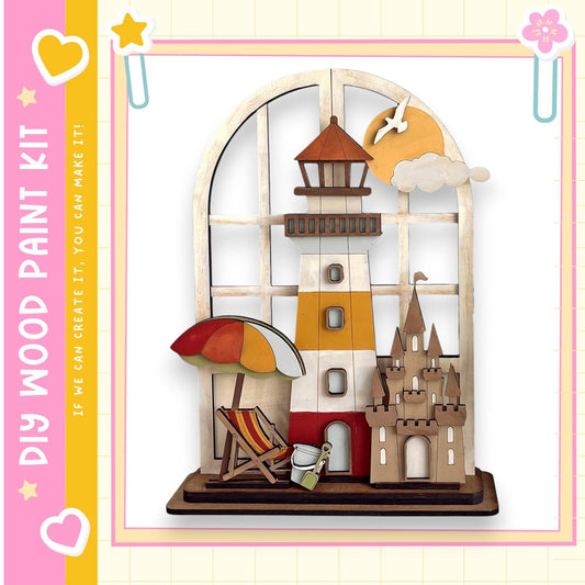 A wooden toy lighthouse with a castle, beach umbrella, and other beach-themed elements, set against a pink and yellow background.