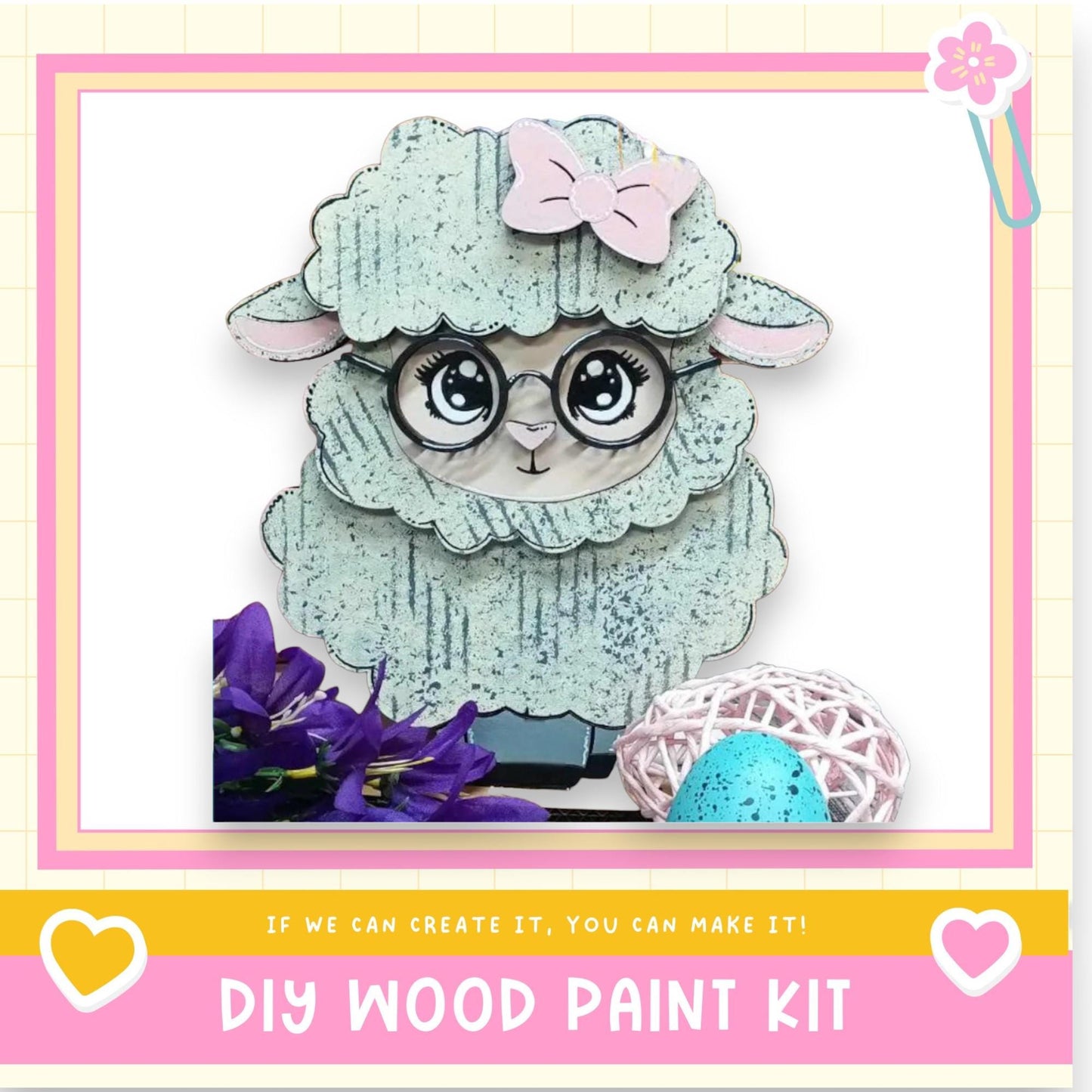 A wooden sheep figure with a bow on its head, surrounded by flowers and a blue egg, with a pink and yellow border.