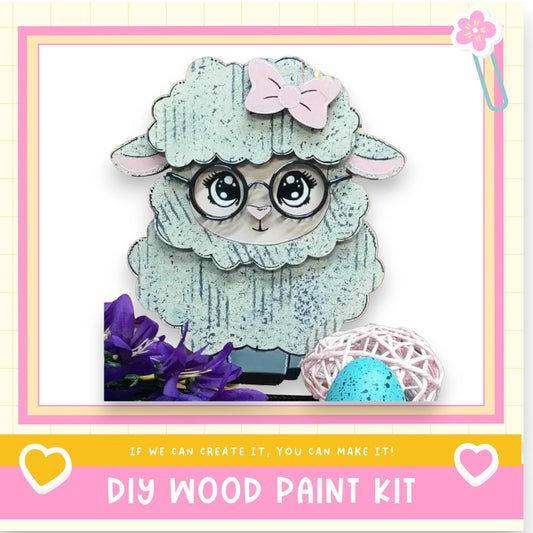 A wooden sheep figure with a bow on its head, surrounded by flowers and a blue egg, with a pink and yellow border.