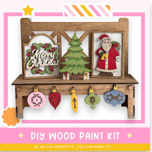 The image is a DIY wood paint kit featuring a wooden shelf with a Christmas tree, a framed image of Santa Claus, and various ornaments hanging from the shelf.