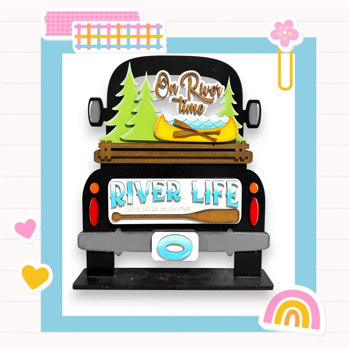 a black truck with a wooden bed, decorated with various objects related to river life, such as a canoe, pine trees, and a sign that says "On River Time".