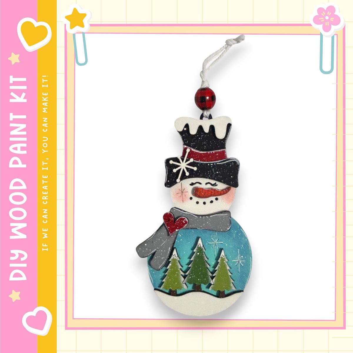 A wooden snowman ornament with a red bow, a black top hat, and a blue scarf, decorated with green pine trees and a blue snowman.