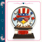 A wooden snow globe with an eagle wearing sunglasses and an American flag hat, surrounded by stars and flowers.