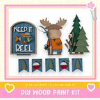 The image is a collage of various wooden craft items, including a moose figure, a fishing rod, and a tree, along with a sign that says "Keep it Reel". The collage also includes a banner with the text "If we can create it, you can make it!" and a heart symbol.