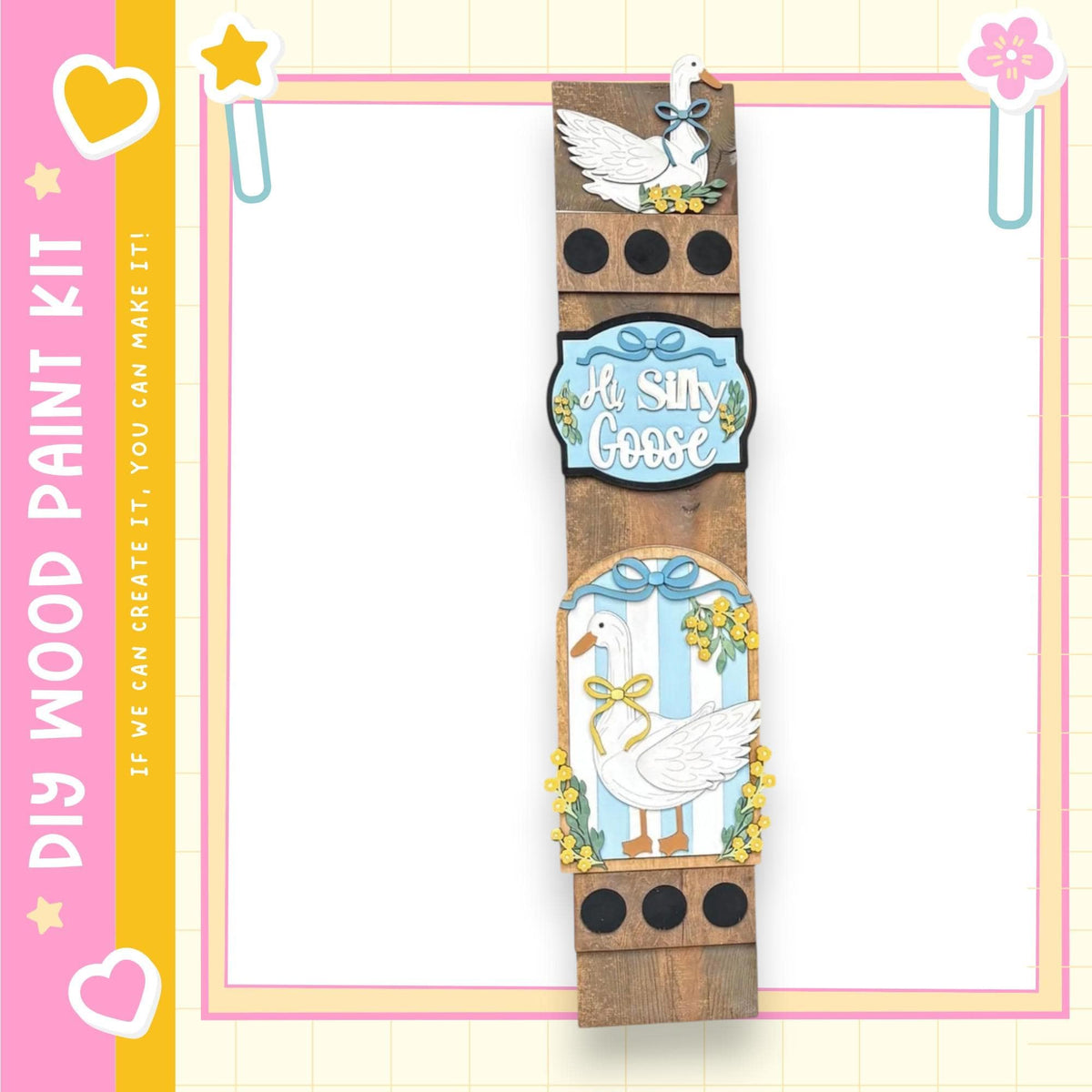 a wooden frame with a decorative design, including a white goose and yellow flowers. The frame is surrounded by a pink and yellow border, and there are decorative elements such as hearts and a star on the border.