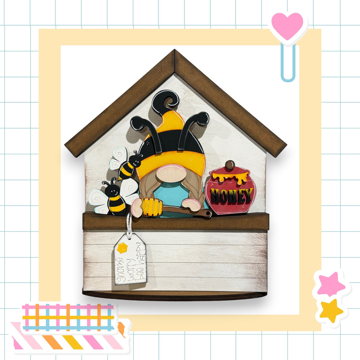 A wooden house-shaped structure with a bee and honey jar on it, surrounded by various colorful stickers and a heart-shaped object.