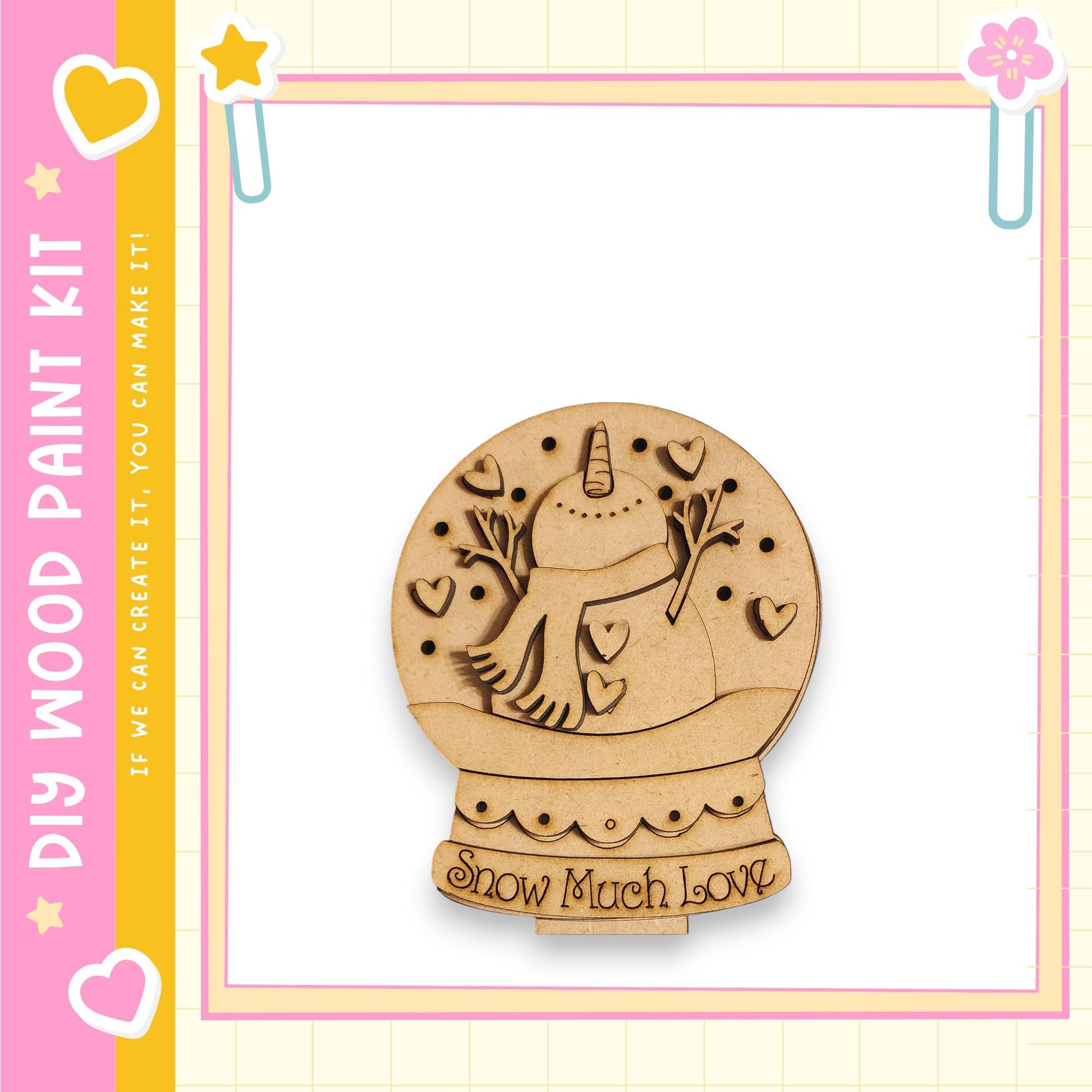 A wooden snow globe with a unicorn and hearts on it, set against a pink and yellow background with decorative elements.