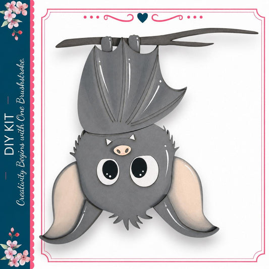 A cute gray bat with large eyes and a pink nose is hanging upside down from a branch, surrounded by a decorative border.