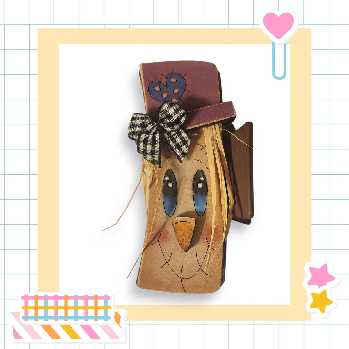 A wooden craft resembling a scarecrow or scarecrow-like figure, with a face and hat, is displayed in a decorative frame.