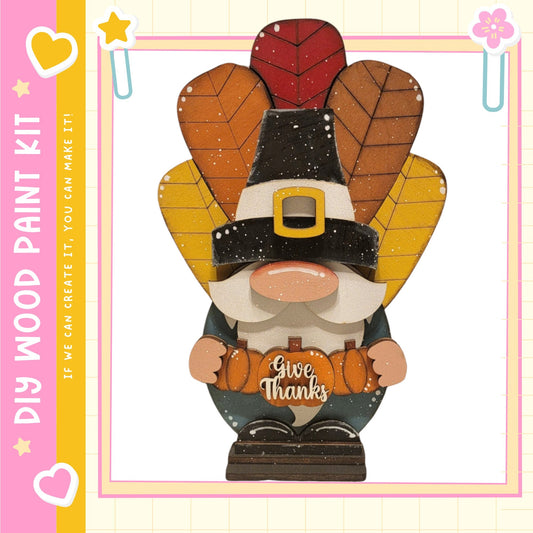 A wooden gnome figure wearing a Thanksgiving-themed hat and holding a carved pumpkin with the text "Give Thanks" on it.
