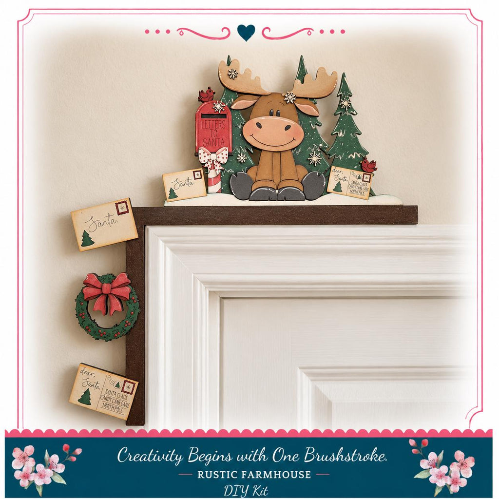 A wooden moose figurine is perched on a shelf above a door, surrounded by holiday decorations such as a wreath, a mailbox, and a "Santa" card.