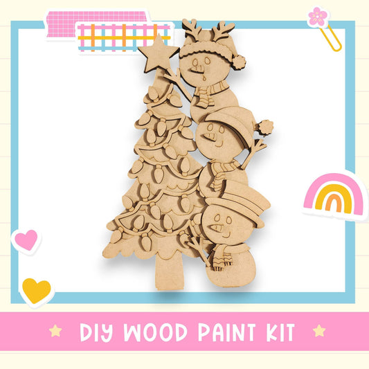 A DIY wood paint kit featuring a wooden Christmas tree with three snowmen and a star on top, surrounded by various colorful stickers and a rainbow.