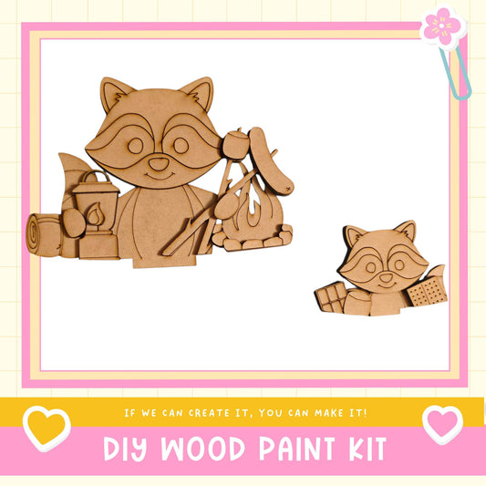 a DIY wood paint kit with two raccoon-shaped figures, one larger and one smaller, along with various craft supplies such as a cup, spoon, and other tools. The kit appears to be designed for creating wooden figures or decorations.