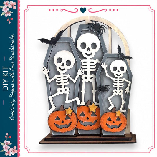 A Halloween-themed DIY kit featuring a skeleton graveyard with carved pumpkins and bats.