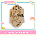 a wooden sign that says autumn with a rainbow in the background